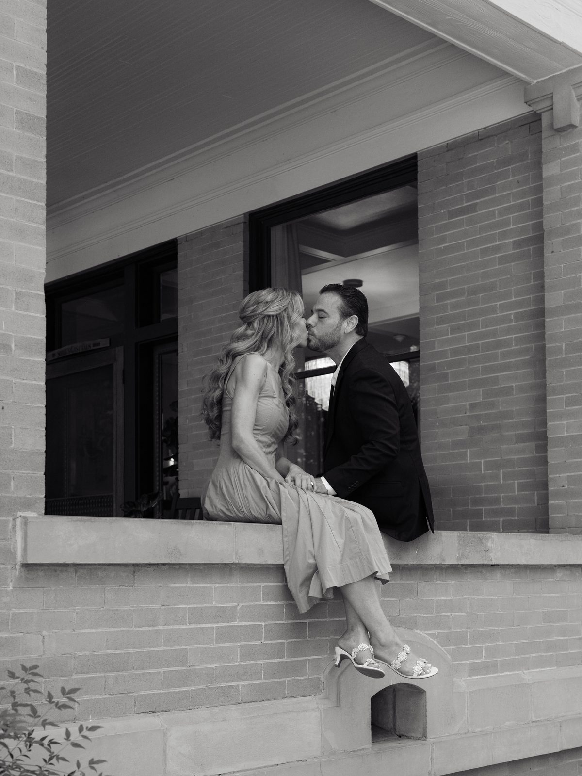 Chris and Brittney kissing on a brick ledge